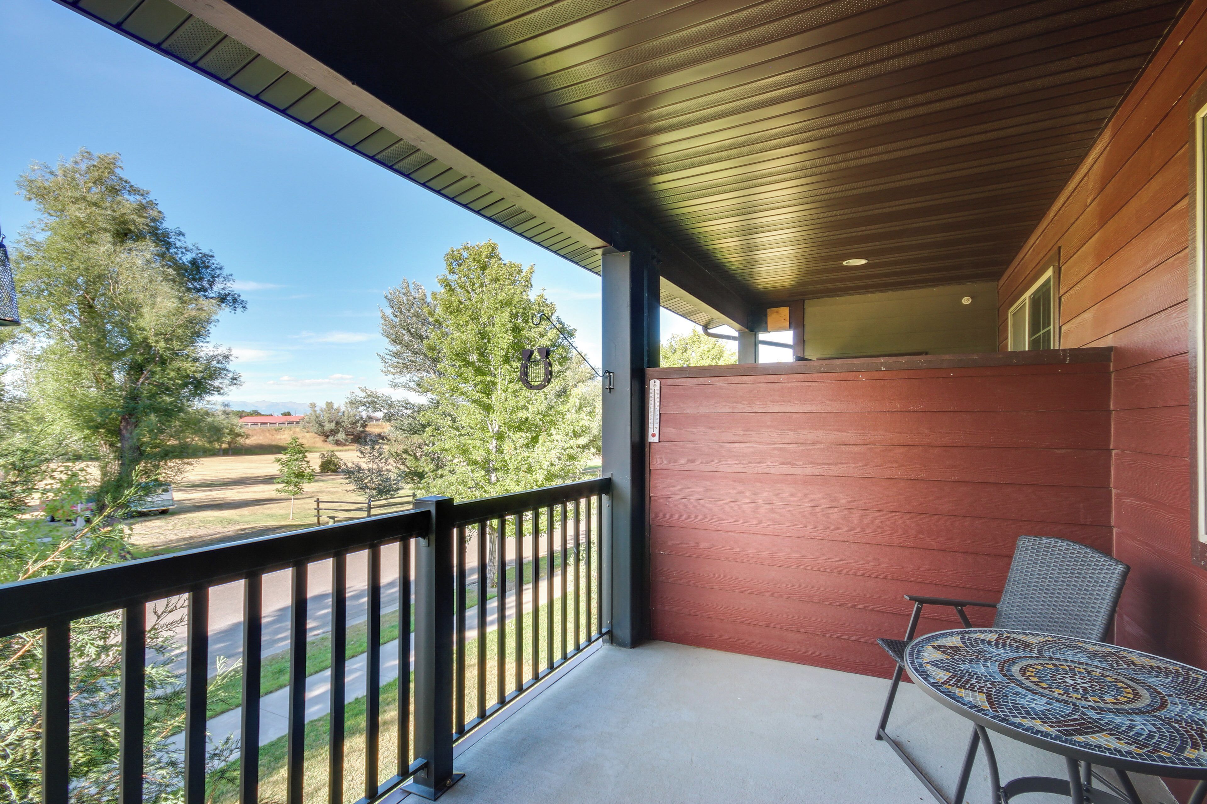 A balcony with a metal railing, a patterned table, and a red wall.