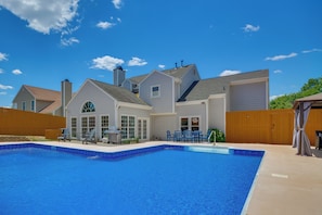 A residential property with a swimming pool, a patio with outdoor furniture, and a large house with multiple windows and a garage. - Graham Home w/ Private Pool & Ping-pong Table! (Graham)