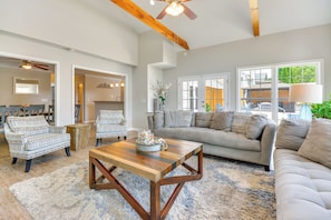 A spacious living room with a wooden coffee table, patterned armchairs, a grey sofa, and large windows. - Graham Home w/ Private Pool & Ping-pong Table! (Graham)