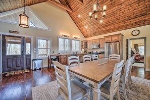 A spacious kitchen with wooden cabinets, a large dining table, and a high ceiling with exposed beams. - Beautiful Lake Views! Glenville Serenity Lodge' (Glenville)