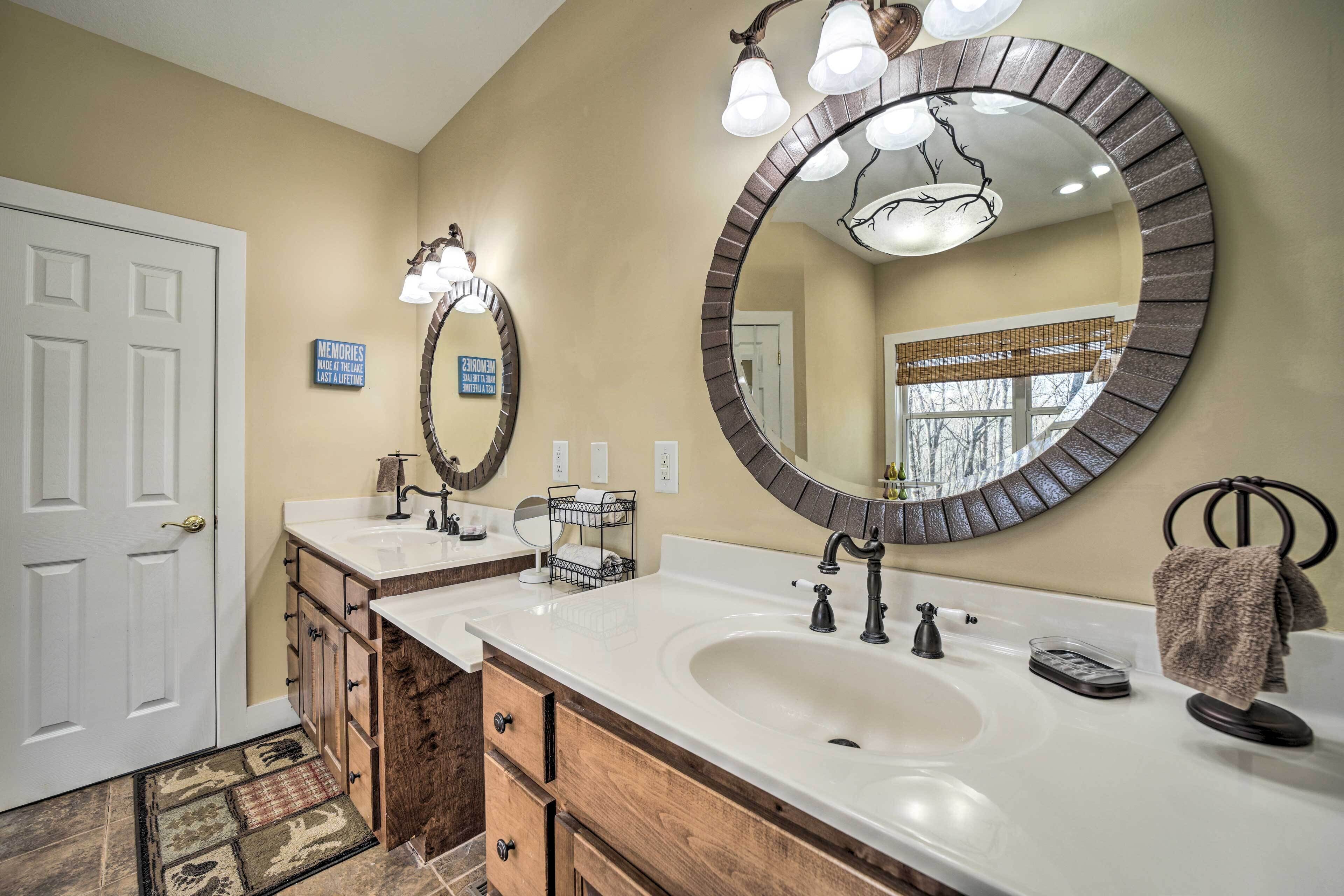 A bathroom with two sinks, wooden cabinetry, and a large mirror with a circular frame.