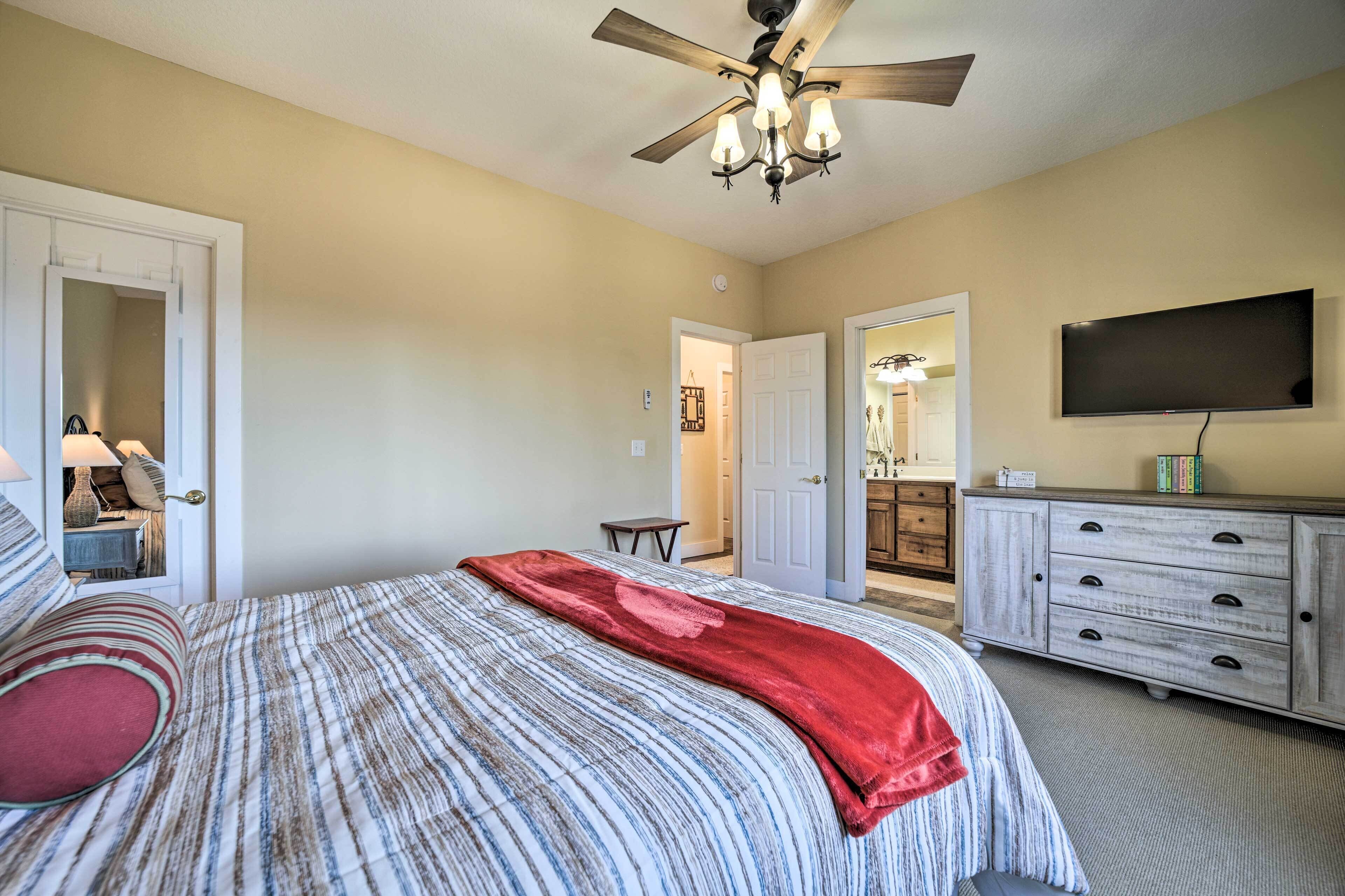 A bedroom with a bed, a ceiling fan, a TV, and a dresser.