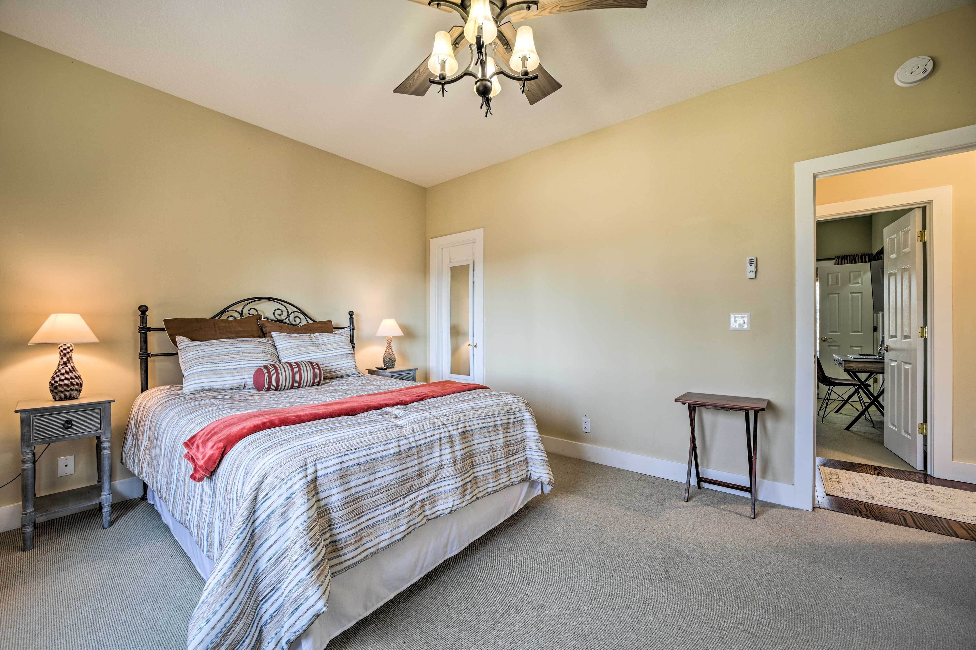 Une chambre à coucher avec un lit, des lampes de chevet, une petite table et une porte donnant sur une autre pièce.