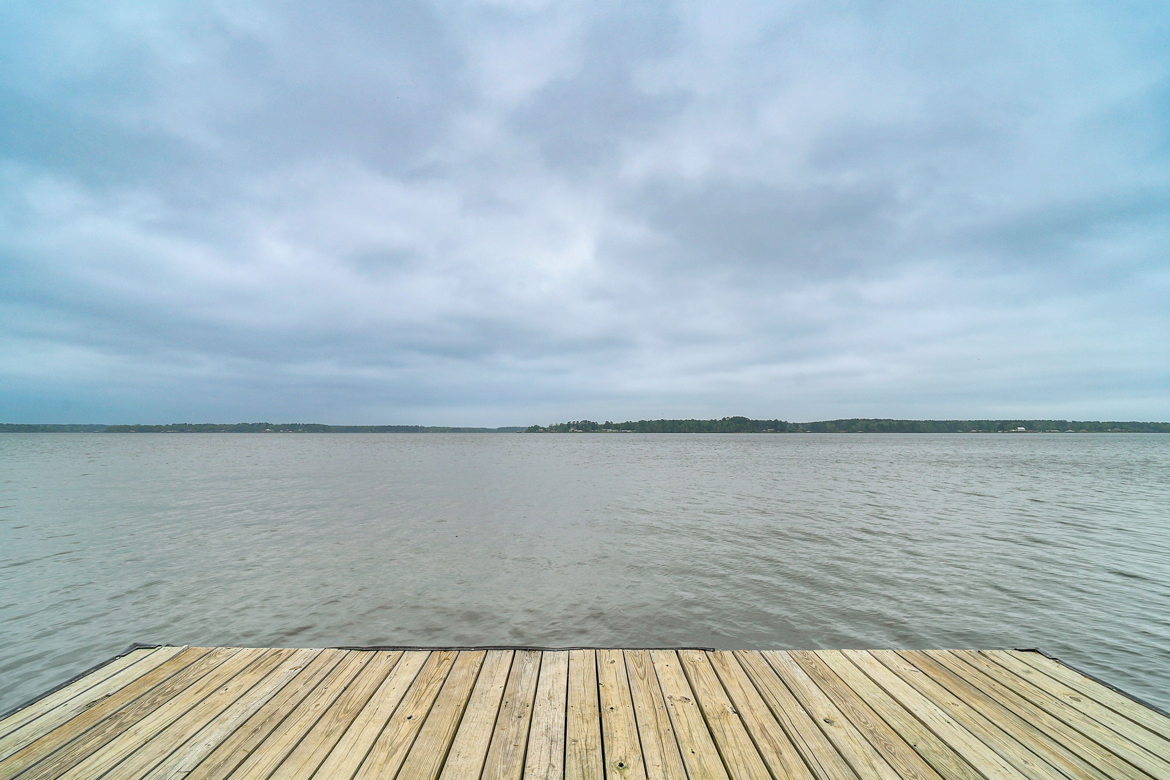 Un muelle de madera que se adentra en un cuerpo de agua tranquilo bajo un cielo nublado.