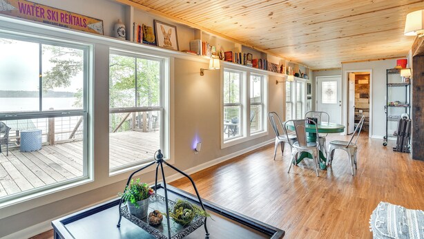 A spacious room with wooden floors, large windows, and a dining area with chairs and a table. - Waterfront House on Toledo Bend w/ Private Dock! (Many)