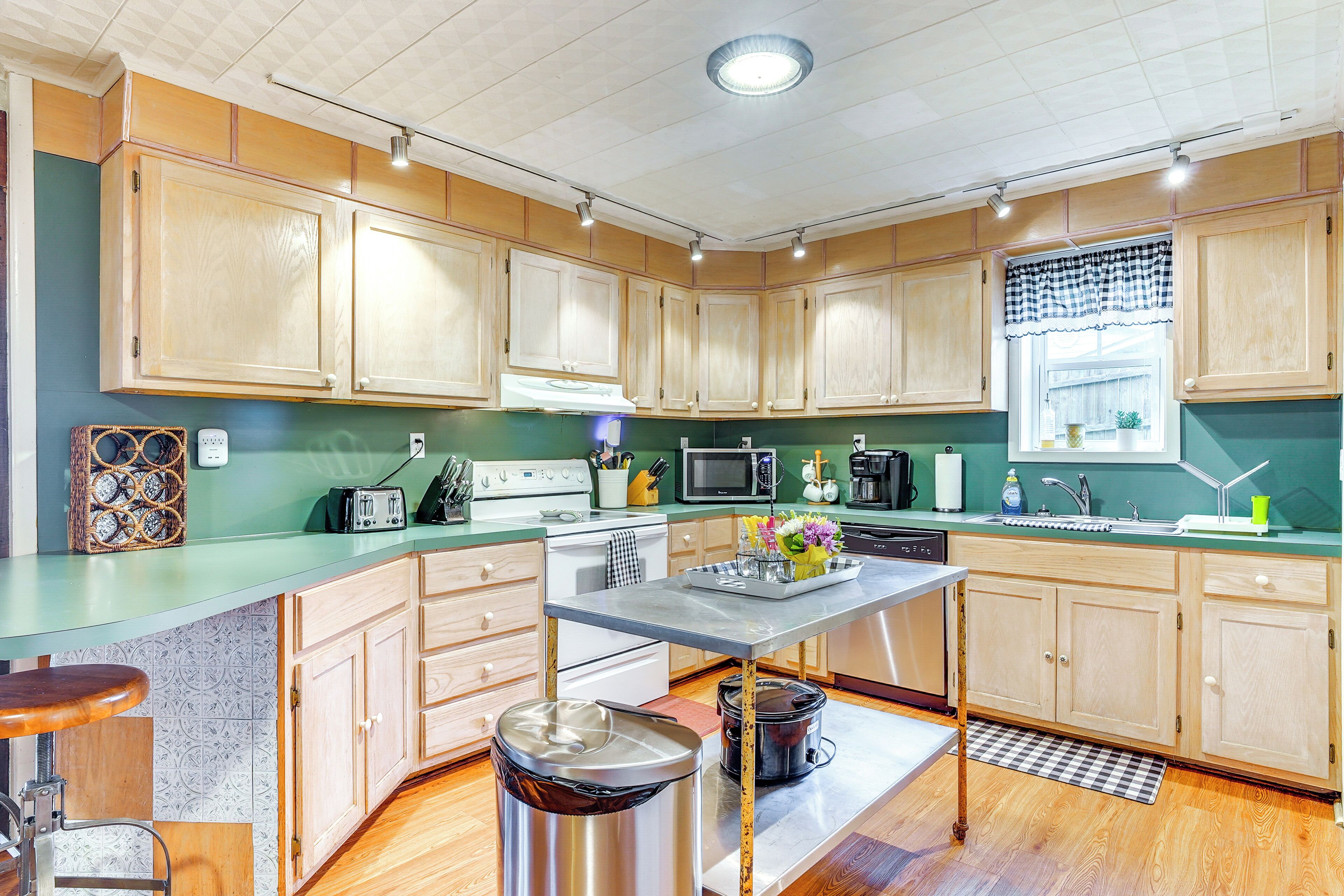 A kitchen with wooden cabinets, a stainless steel sink, a microwave, and a stove.