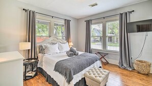 A bedroom with a bed, bedside tables, a lamp, a TV, and a window with curtains.