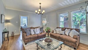 A living room with two brown leather sofas, a glass coffee table, and a chandelier.
