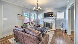A living room with a fireplace, leather sofas, and a chandelier.