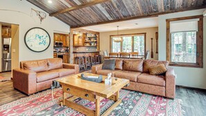 A spacious living area with a large sectional sofa, a wooden coffee table, and a rustic ceiling.