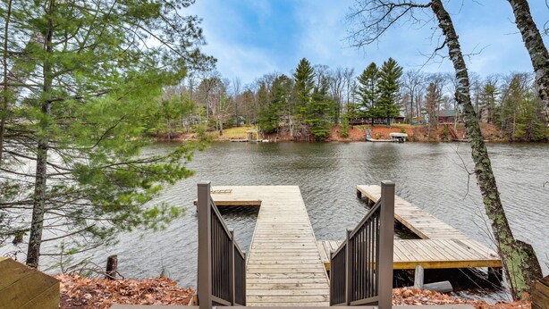A wooden dock leading into a lake surrounded by trees.