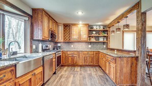 A kitchen with wooden cabinets, granite countertops, and a tiled backsplash.