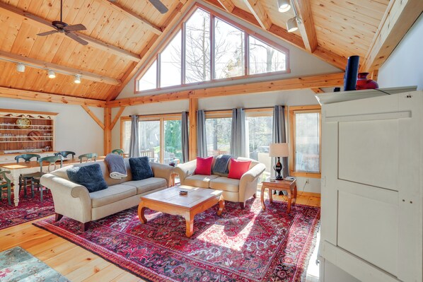 A spacious living room with high ceilings and large windows, featuring two sofas, a coffee table, and a dining area with chairs and a table. - 'luna Stella' - West Dover Home 1 Mi to Mt Snow! (West Dover)