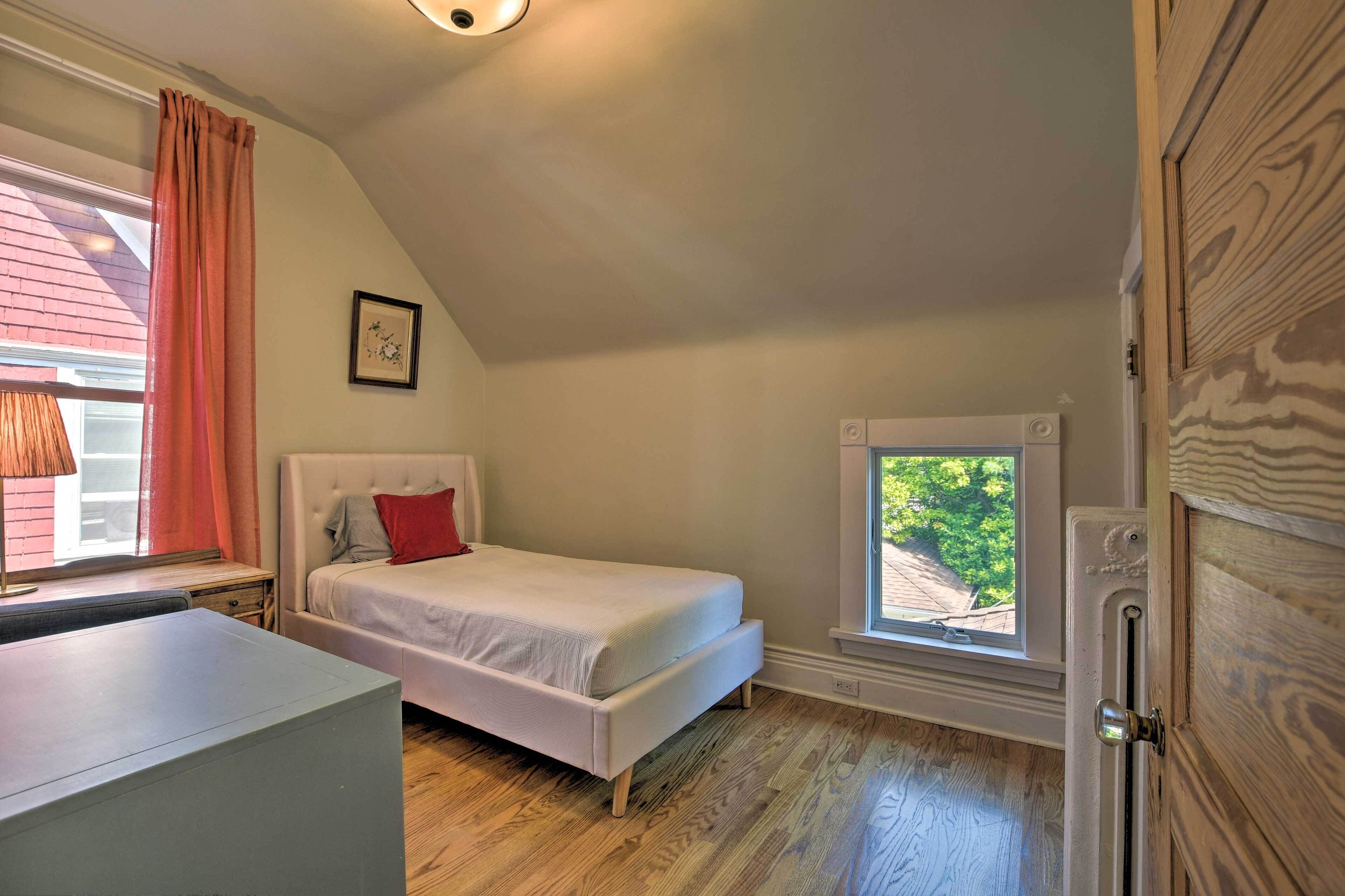 Une chambre à coucher avec un lit, un bureau, une fenêtre et une porte.