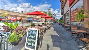 An outdoor cafe with red umbrellas, outdoor seating, and a chalkboard sign advertising delivery. - Classic Oak Park Home, 11 Mi to Downtown Chicago! (Oak Park)
