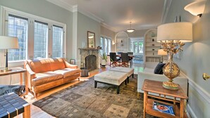 A spacious living room with a leather sofa, a fireplace, and a dining area. - Classic Oak Park Home, 11 Mi to Downtown Chicago! (Oak Park)