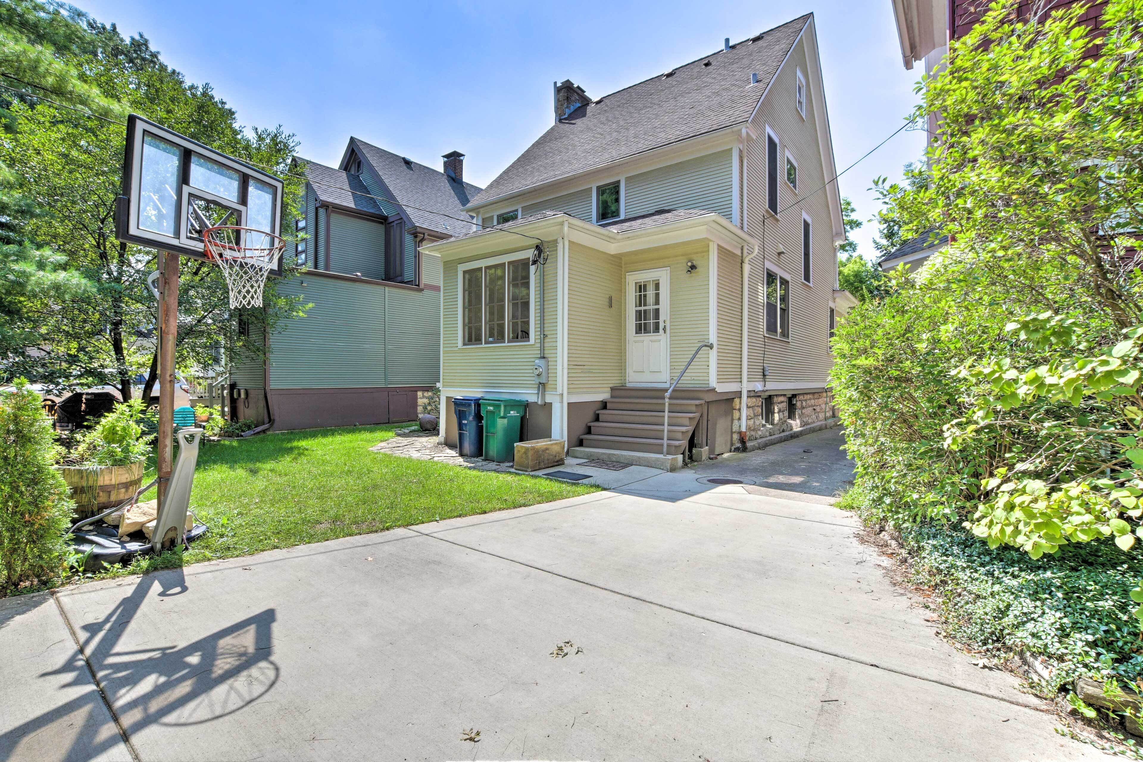 A residential house with a front yard, a basketball hoop, and a staircase leading to the front door.