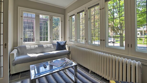 A living room with a sofa, a glass coffee table, and large windows with a view of the street. - Classic Oak Park Home, 11 Mi to Downtown Chicago! (Oak Park)