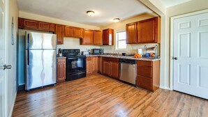 Una cocina con armarios de madera, electrodomésticos de acero inoxidable y suelo de madera.