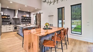 A modern kitchen with a central island, built-in appliances, and large windows offering views of the outdoors. - Boat Dock & Slip: Riverfront Home in Heber Springs (Heber Springs)