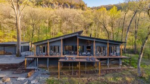 A modern house with a deck, large windows, and a stone staircase leading to the entrance. - Boat Dock & Slip: Riverfront Home in Heber Springs (Heber Springs)