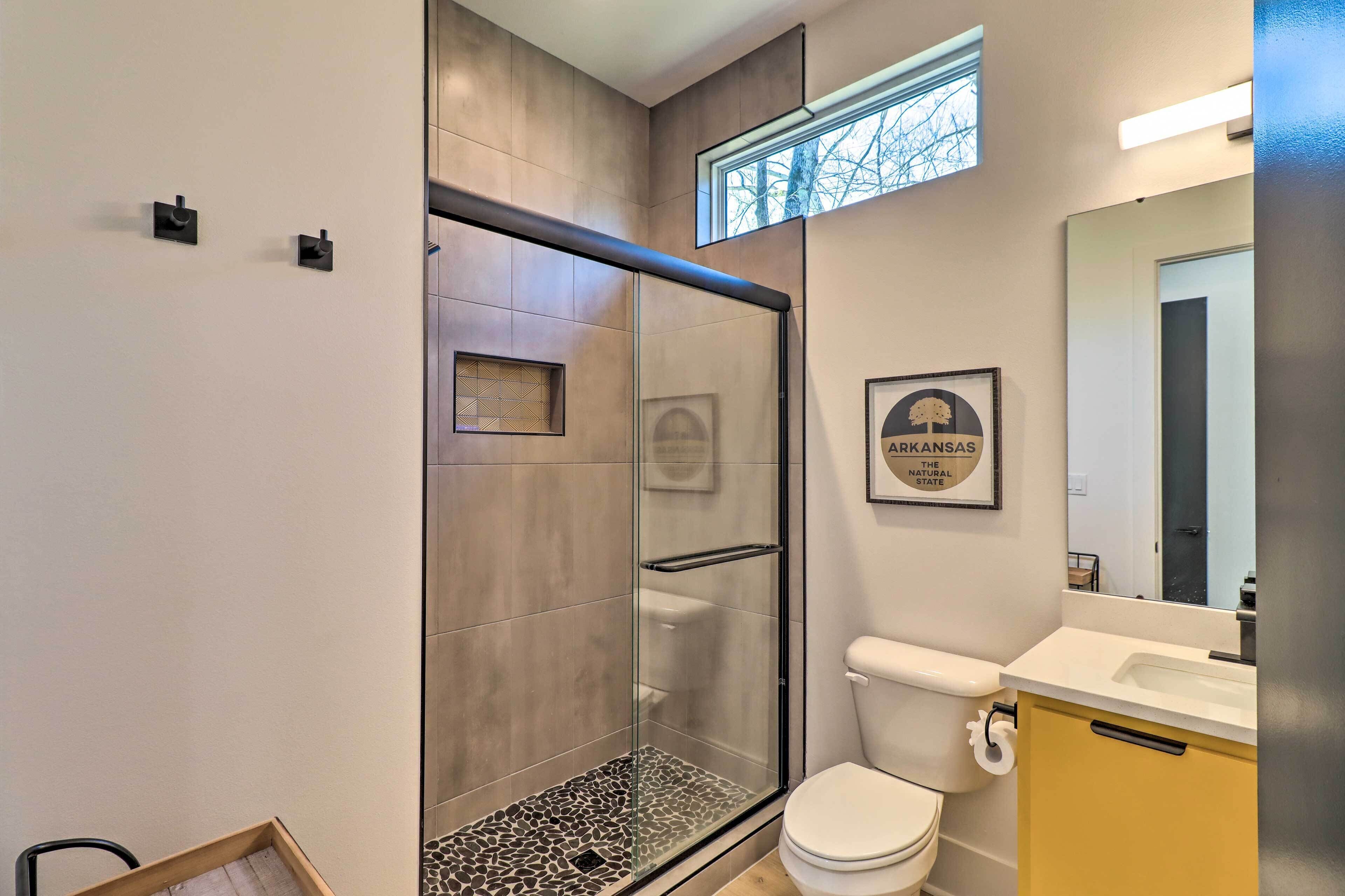 A modern bathroom with a glass-enclosed shower, a toilet, and a sink.