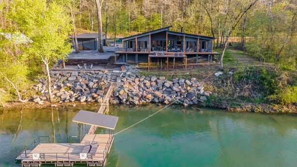 A lakeside cabin with a dock, surrounded by trees and a rocky shoreline. - Boat Dock & Slip: Riverfront Home in Heber Springs (Heber Springs)