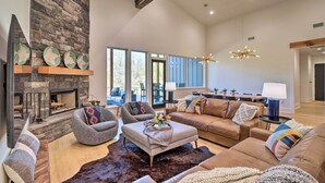 A spacious living room with a stone fireplace, comfortable seating, and a modern chandelier. - Boat Dock & Slip: Riverfront Home in Heber Springs (Heber Springs)