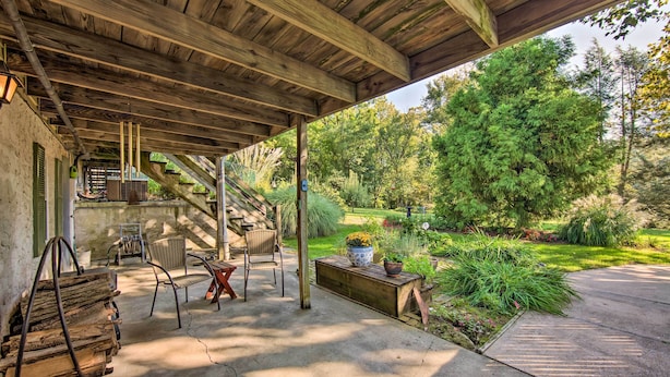 A covered patio with wooden furniture, a stone bench, and a potted plant.