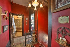 A room with red walls, a chandelier, a mirror, and a door leading to another room. - Vintage Apartment in Historic Downtown La Porte (La Porte)