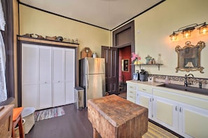 Cozinha compacta com um banco de madeira, uma geladeira e uma pia.