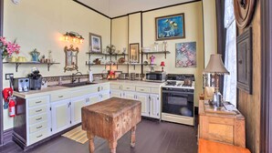 A kitchen with white cabinets, a wooden bench, a stove, and various kitchen appliances. - Vintage Apartment in Historic Downtown La Porte (La Porte)