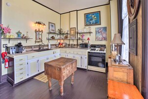 Una cocina con armarios blancos, un banco de madera, una estufa y varios electrodomésticos.