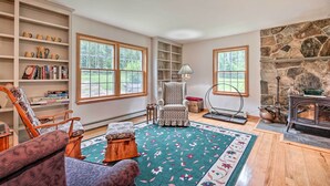 A cozy living room with a fireplace, wooden floors, and large windows. - Wilmington Home on 18 Acres ~ 9 Mi to Skiing! (Wilmington)