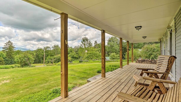 A covered wooden deck with outdoor seating and a view of a grassy field and trees. - Wilmington Home on 18 Acres ~ 9 Mi to Skiing! (Wilmington)
