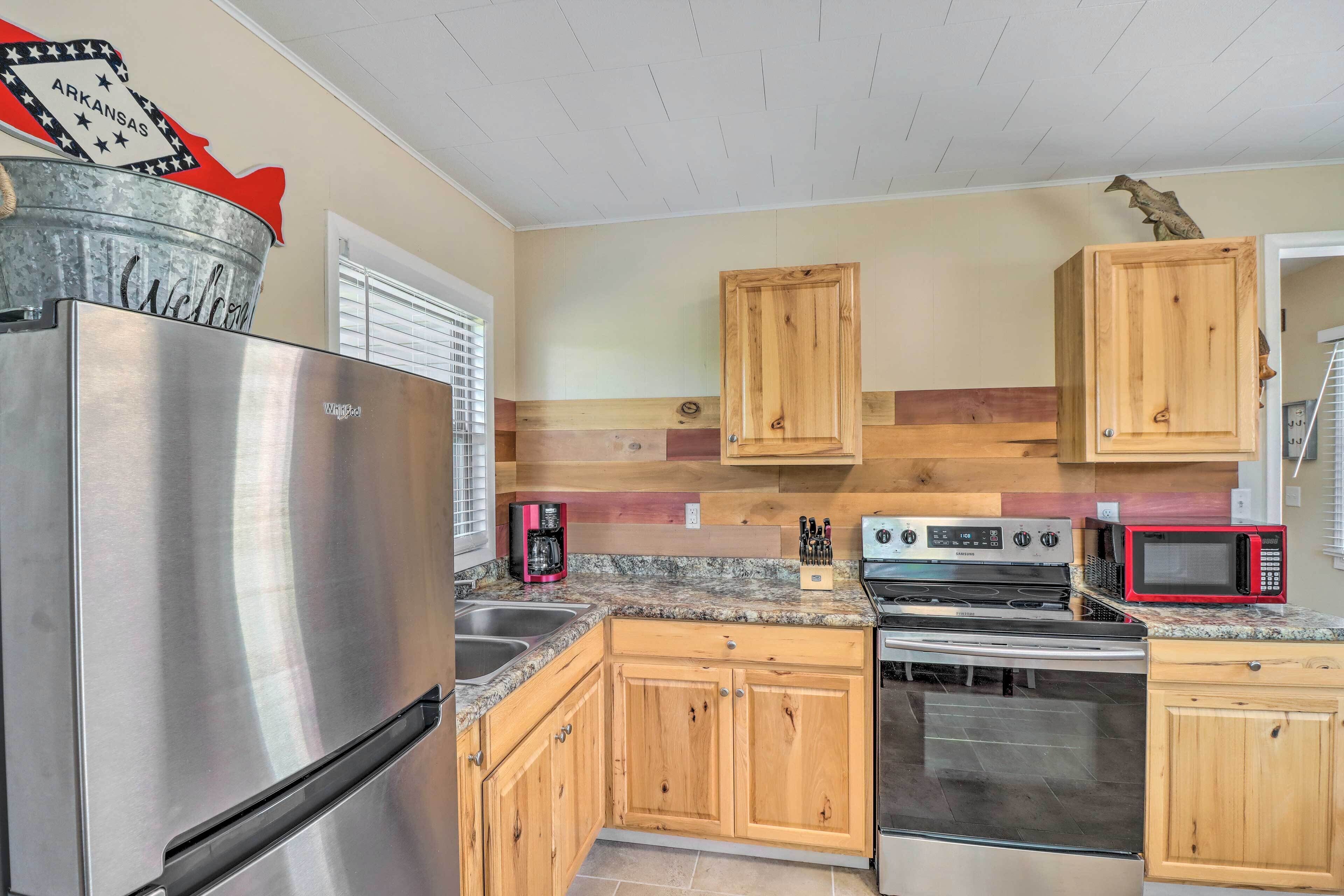 A kitchen with wooden cabinets, a stainless steel refrigerator, a stove, and a microwave.