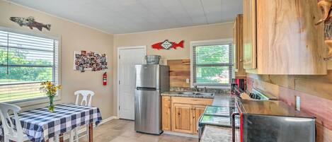 A kitchen with a dining table, chairs, a refrigerator, a microwave, and wooden cabinets.