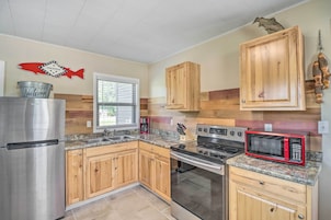 A kitchen with wooden cabinets, a stainless steel refrigerator, a microwave, and a stove.