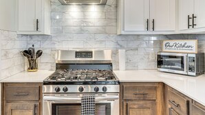 Una cocina moderna con armarios blancos, estufa de acero inoxidable y microondas.
