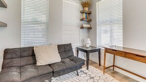 Una sala moderna con un sofá gris oscuro, una mesita pequeña y un escritorio de madera.