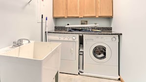 Un espace buanderie comprenant un lave-linge, un sèche-linge et un évier.