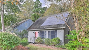Une maison dotée de panneaux solaires, d’une porte rouge et d’un jardin bien entretenu.