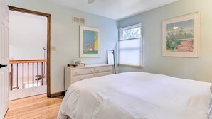 Une chambre avec un grand lit, une commode, un ventilateur de plafond et des œuvres d’art accrochées aux murs.