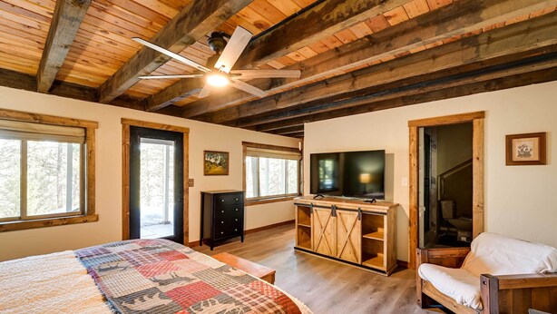 Una habitación acogedora con una cama grande, televisión, una silla de madera y un escritorio.