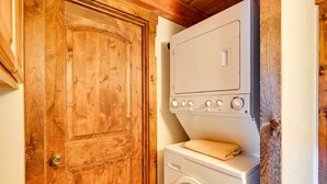 Un lavadero con una puerta de madera y una lavadora y secadora apiladas.