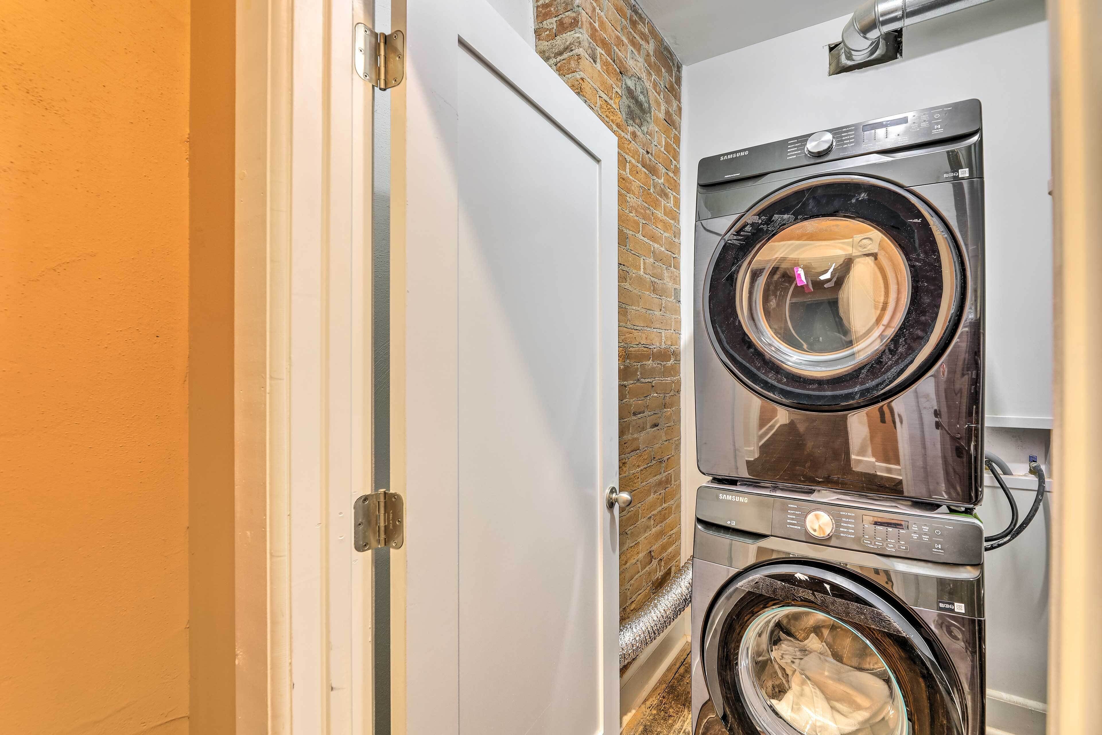 A laundry room with two stacked front-loading washing machines and a door to the left.
