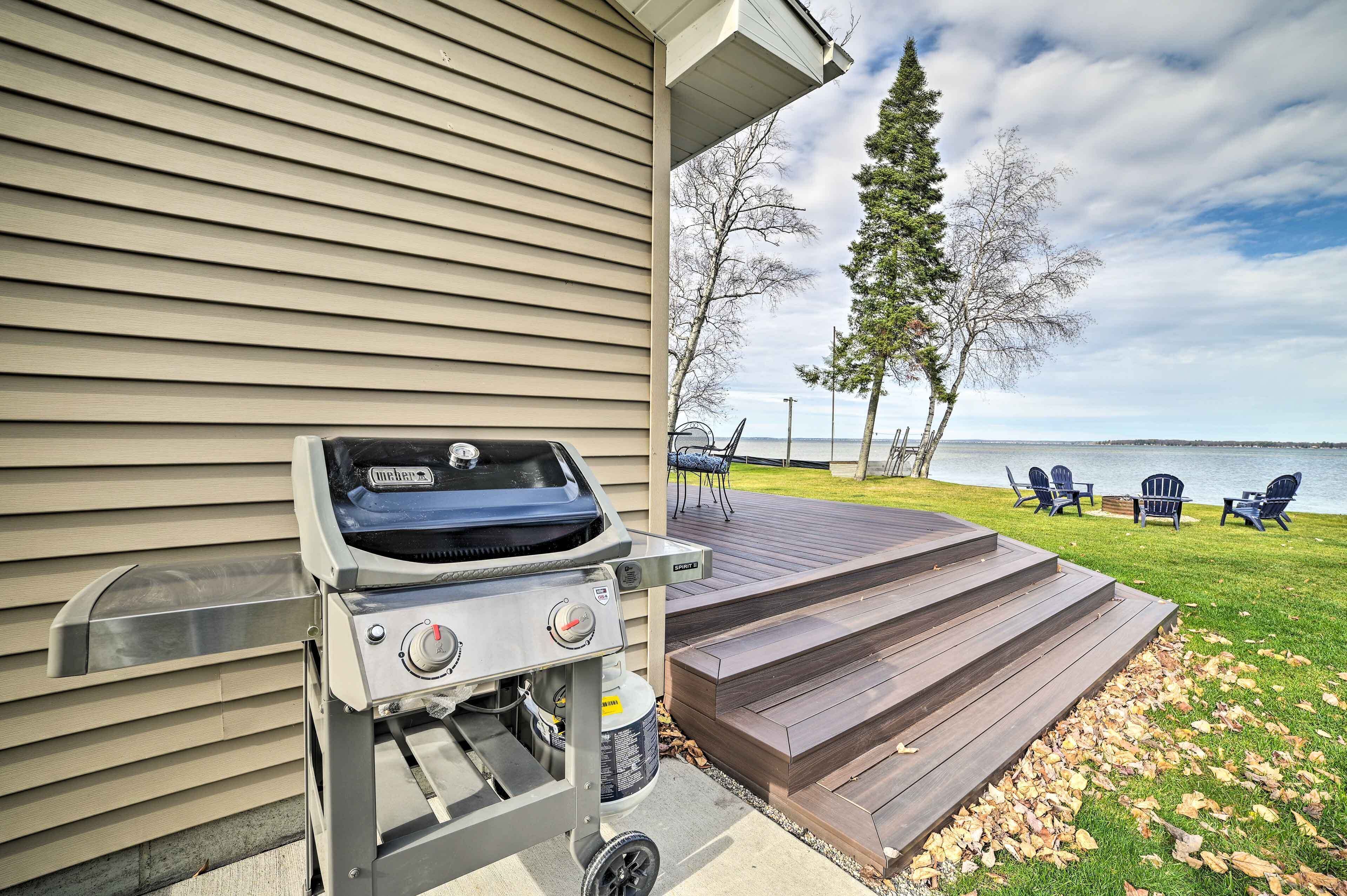 A patio with a grill, outdoor seating, and a view of the lake.