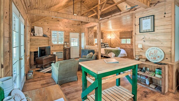 L’intérieur d’un chalet accueillant, avec des murs et des planchers en bois, une table à manger, un canapé et un téléviseur en arrière-plan.