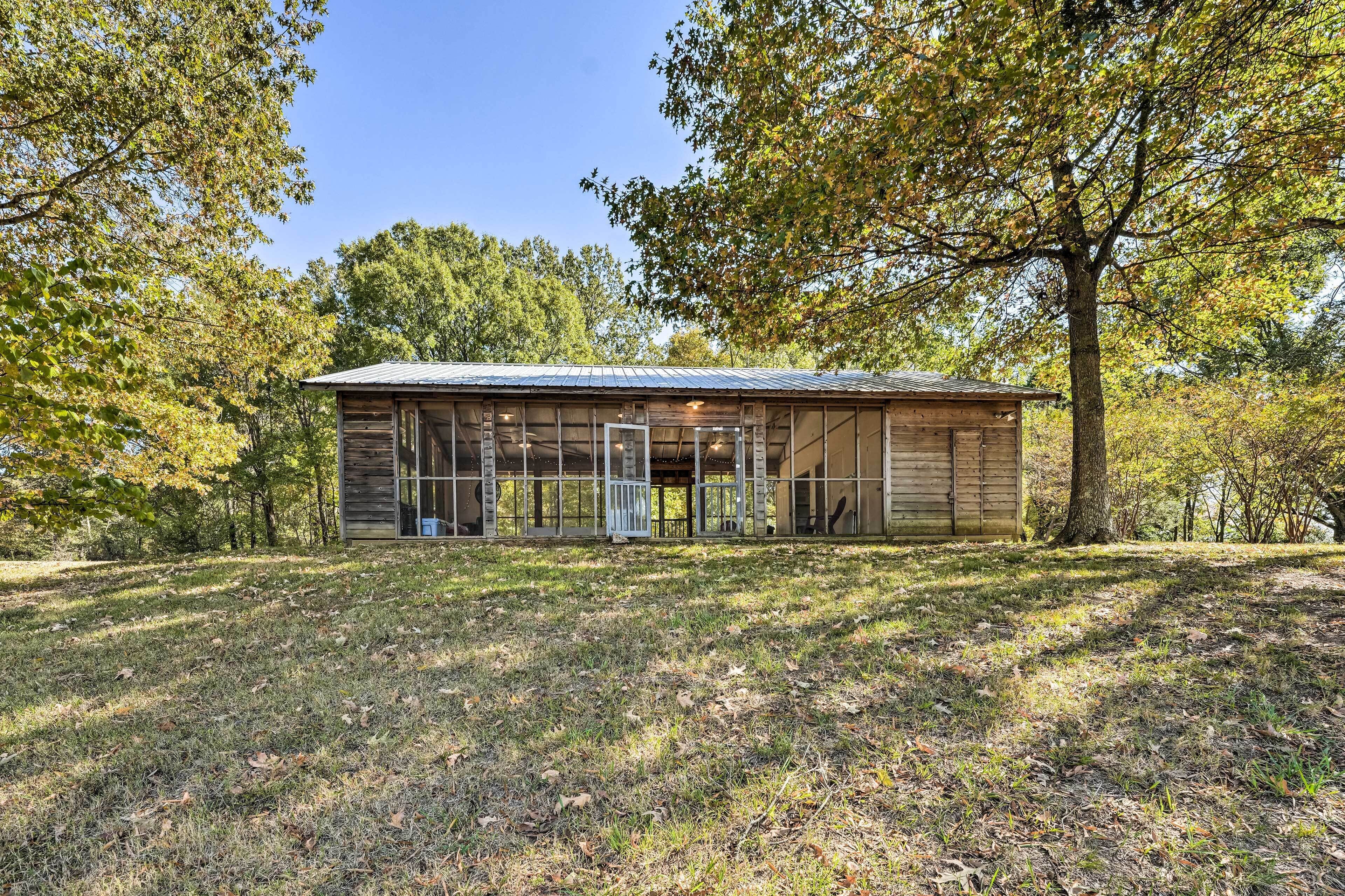 A wooden cabin with a metal roof, surrounded by trees and grass.