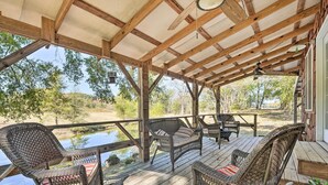 Une terrasse couverte, aménagée avec des meubles en osier, offrant une vue sur un paysage naturel.